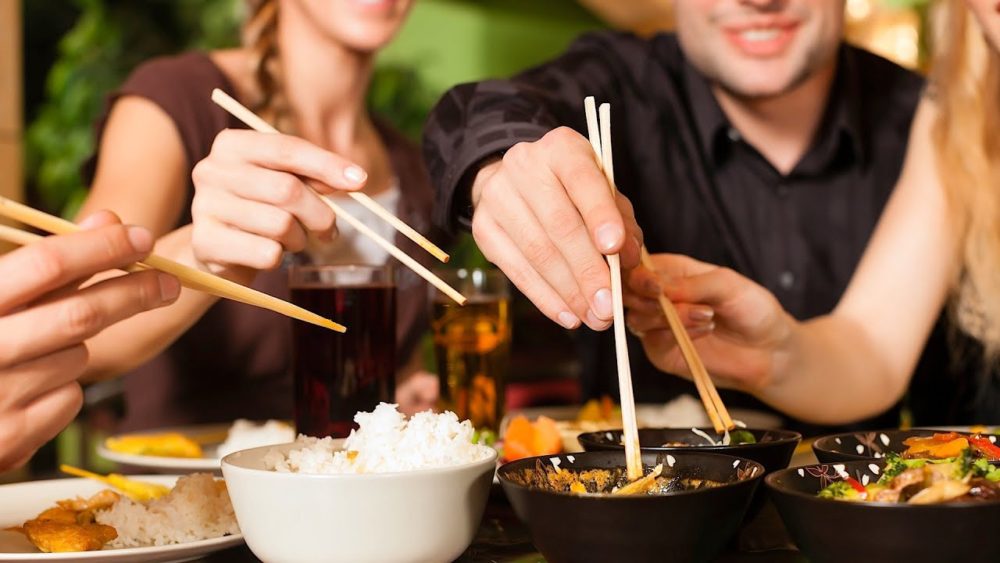 Several people eating Korean food with chopsticks