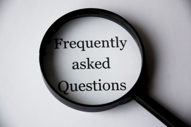 magnifying glass over black and white words saying frequently asked questions 