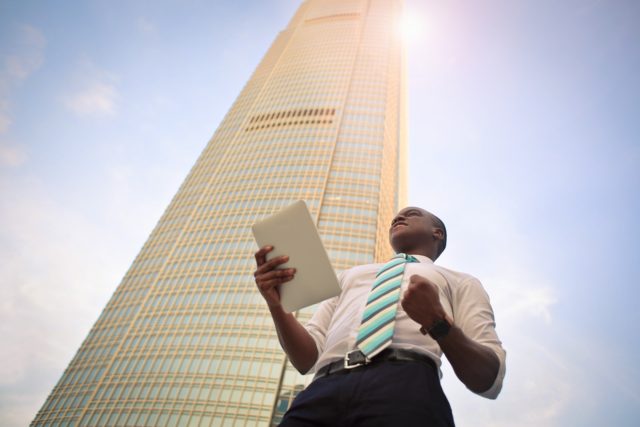 young business man being successful and smiling in front of a tall building