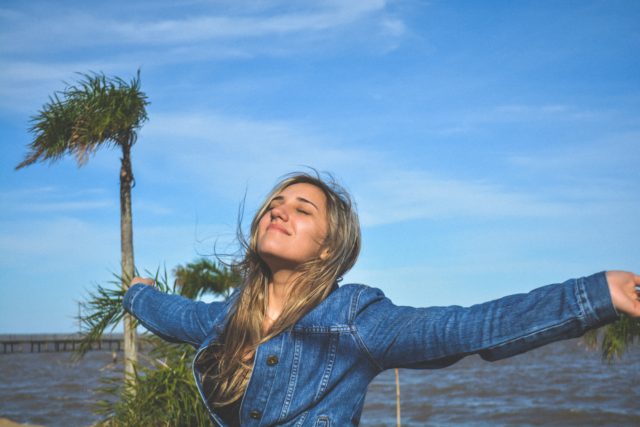 girl stretching out her arms and smiling on a sunny day at a peer
