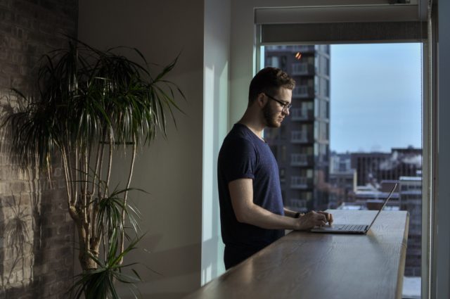 man typing on his laptop on the kitchen counter