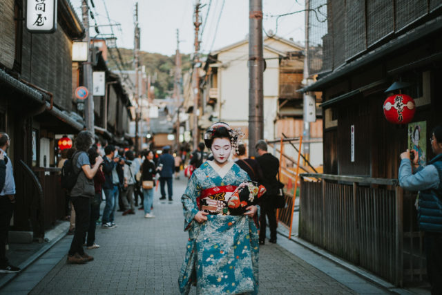 woman in white and blue floral kimono walking down a traditional street in Japan
