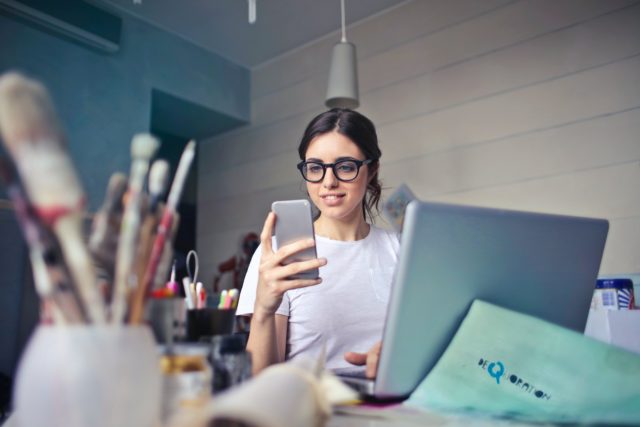 woman working on her laptop and phone to improve her social media presentation