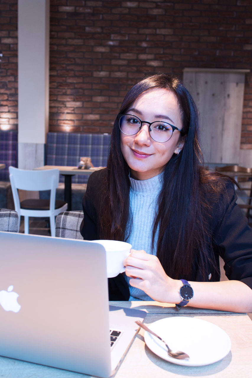 Meiji's Intern Cindy working remotly from a Café with her laptop and a coffee