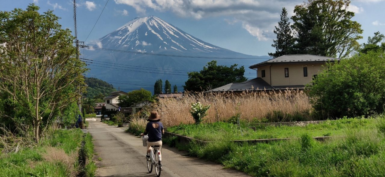 Woman riding bicycle through the countryside of Japan, beneath Mt. Fuji