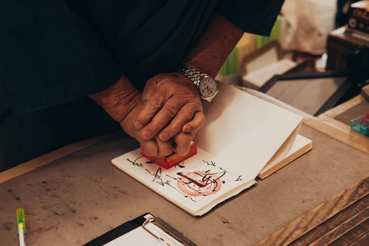 Japanese man stamps a booklet with a tradition hanko stamp