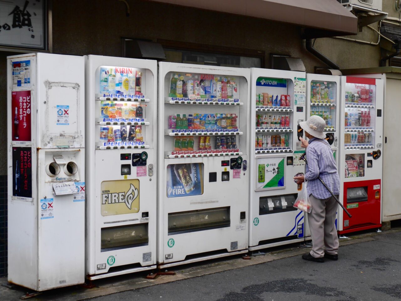 A Japanese woman purchasing a drink at a vending machine.