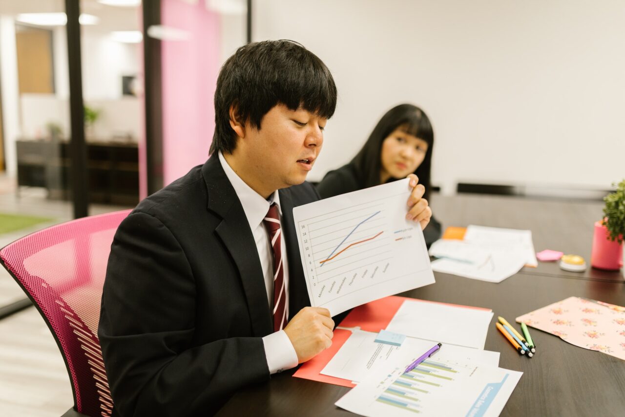 A young Japanese business man demonstrating business etiquette by holding a pre printed document for his presentation.