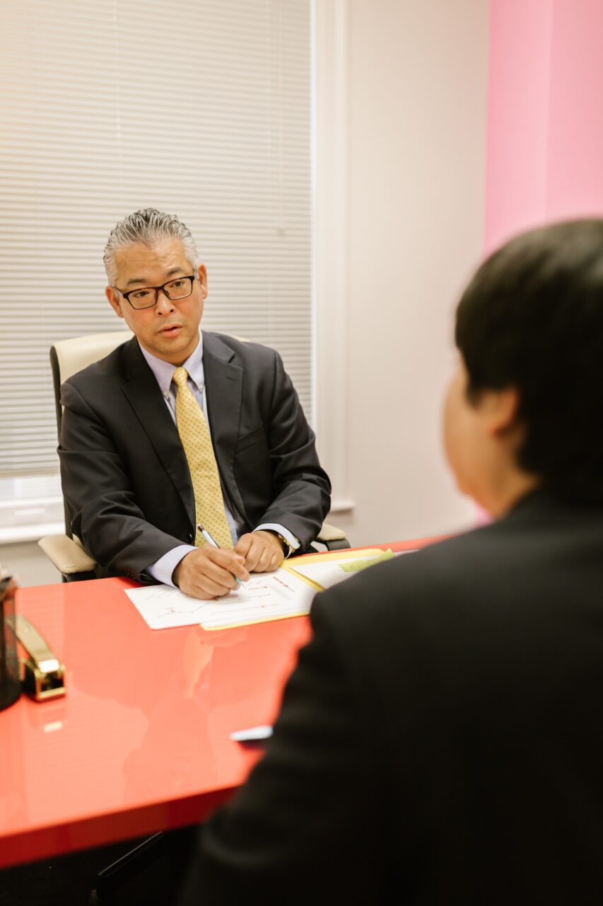 An older business man discussing business with a younger business man in a office.